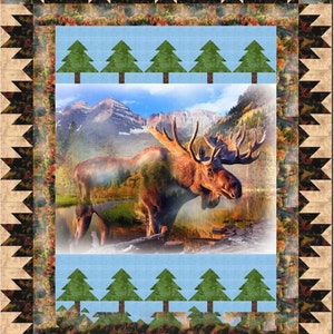 May include: A quilt featuring a moose standing in a lake with mountains in the background. The quilt has a blue and green border with a pattern of trees.