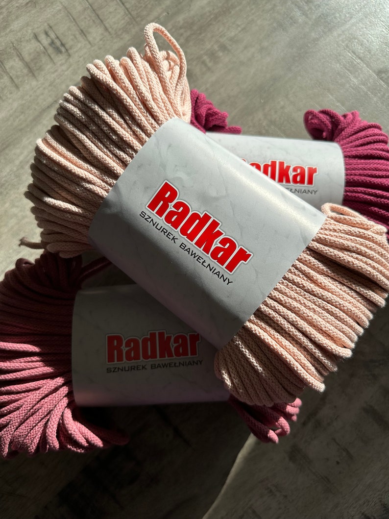 May include: Two spools of cotton cord, one pink and one burgundy, with the label "Radkar Sznurek Bawelniany" on the pink spool.