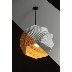 May include: A white and gold geometric pendant light fixture with a textured, honeycomb-like design. The light is hanging from a black cord.