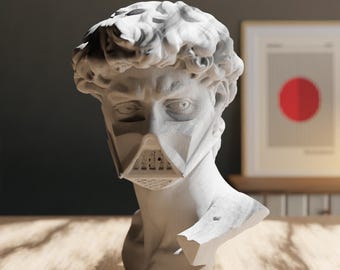 Op de afbeelding: Een wit gipsen buste van een man met een wit gezichtsmasker met een geometrisch ontwerp. De buste staat op een houten tafel.