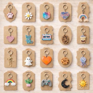 May include: A collection of keychains with various designs, including a paw print, daisy, heart, rainbow, cat, and ghost. Each keychain is attached to a brown card with a metal ring.