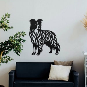 May include: Black silhouette of a border collie dog with intricate floral patterns cut out of the shape. The silhouette is mounted on a white wall above a black couch.