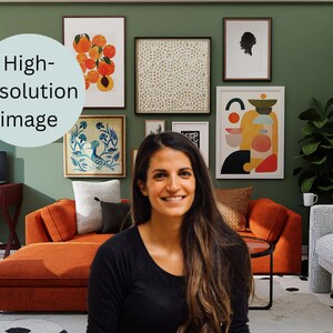 Puede incluir: Una mujer con el pelo largo y castaño sonríe frente a una pared verde con una pared de galería de obras de arte enmarcadas. Las obras de arte incluyen diseños abstractos, un pájaro y un bodegón de naranjas. La habitación está decorada con un gran sofá naranja, una silla blanca y una planta en maceta.