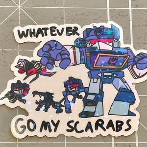 Peut inclure: Un autocollant repr&eacute;sentant un robot de dessin anim&eacute; avec le texte "WHATEVER GO MY SCARABS". Le robot est principalement bleu avec des accents violets et rouges. Plusieurs petits robots et cr&eacute;atures entourent la figure principale, avec une finition scintillante.
