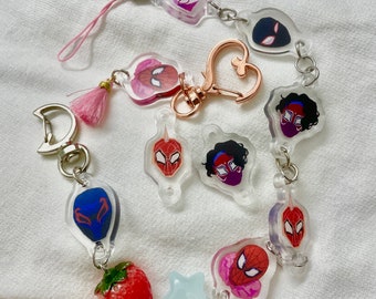 Puede incluir: Una colección de colgantes acrílicos transparentes con varios diseños de personajes de Spider-Man. Los colgantes están conectados con anillos metálicos y un cierre en forma de corazón. Incluye un colgante de fresa roja y una estrella azul claro.