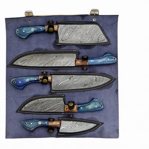 Op de afbeelding: Set van vijf keukenmessen met blauwe en bruine handvatten, gepresenteerd in een blauwe leren rol met individuele vakken voor elk mes.
