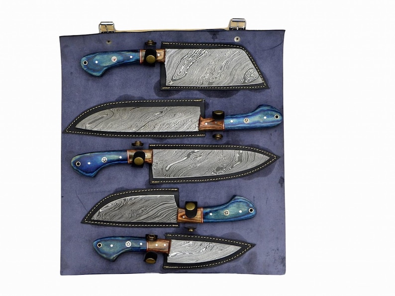 Op de afbeelding: Set van vijf keukenmessen met blauwe en bruine handvatten, gepresenteerd in een blauwe leren rol met individuele vakken voor elk mes.