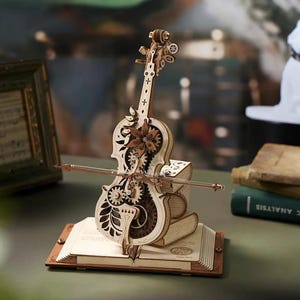 May include: A wooden violin model with intricate gear and floral designs. The model sits atop a stack of books and a wooden base. The bow is positioned across the violin. The color palette is primarily natural wood tones.