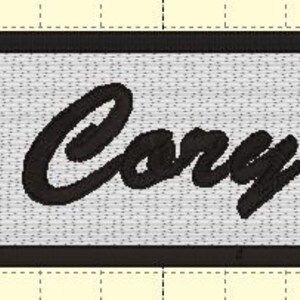 May include: Black embroidered patch with a white background and the name "Cory" written in a cursive font.
