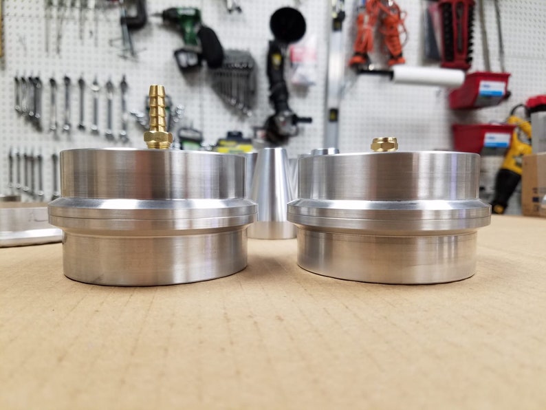 May include: Two silver metal cylinders with a brass fitting on top. The cylinders are stacked on top of each other and have a smooth, polished finish.