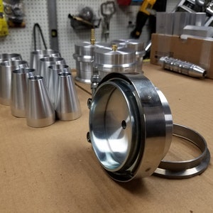 May include: A set of silver metal plumbing parts, including a large round piece with a smaller round piece attached to it, and several smaller cone-shaped pieces.