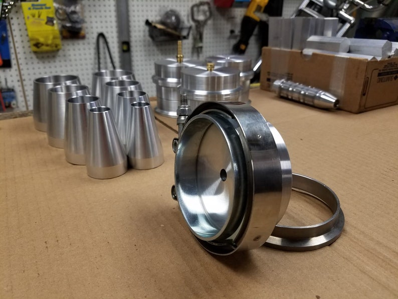 May include: A set of silver metal plumbing parts, including a large round piece with a smaller round piece attached to it, and several smaller cone-shaped pieces.