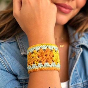 May include: A crocheted cuff bracelet in shades of yellow, orange, and light blue. The bracelet features a floral design and is worn on a wrist. The text "Pattern in 4 Languages" is visible at the bottom of the image.
