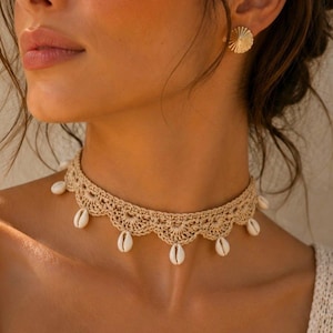 May include: A beige crochet choker necklace adorned with small seashells. The necklace is worn by a person with a gold earring and a white top. The image has the text "Pattern in 4 Languages" at the bottom.