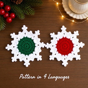 May include: Two crocheted snowflake coasters with white edges and solid centers, one in dark green and one in red. The text "Pattern in 4 Languages" is printed at the bottom. The coasters are arranged on a dark surface with pine branches and a cup.