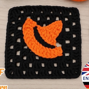 Puede incluir: Un cuadrado de ganchillo negro con un diseño de sombrero naranja, acompañado de ovillos de lana negros y naranjas, y un ganchillo rojo. La imagen también incluye el texto "PDF Pattern" y un icono de bandera con las letras EN, FR, DE y ES.