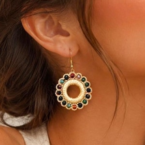 May include: Gold-tone hoop earrings with a circular design. The earrings feature a central open circle surrounded by colorful beads in red, green, black, and yellow. The text "Pattern in 4 Languages" is at the bottom.