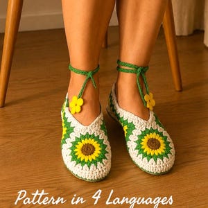 Puede incluir: Un par de zapatillas de ganchillo hechas a mano con un motivo de girasol en hilo blanco, verde y amarillo. Las zapatillas tienen lazos trenzados verdes en el tobillo con pequeños detalles de flores amarillas. El texto "Pattern in 4 Languages" es visible.