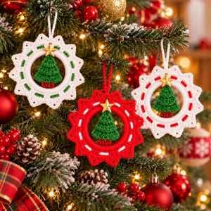 May include: Three crocheted Christmas ornaments featuring a circular star-shaped frame with a small green tree in the center. Two ornaments are white with green accents, and one is red with white accents. Each tree is topped with a gold star.