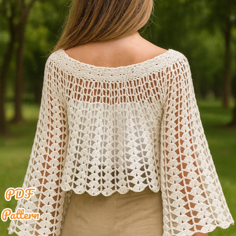 May include: Cream-colored crochet top with a wide neckline and bell sleeves. The top features an open, lacy pattern and a scalloped hemline. The text "PDF Pattern" is visible in the lower left corner. The top is made of a soft, lightweight yarn.