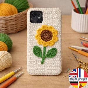 May include: Cream-colored crochet phone case featuring a yellow and brown sunflower design with green leaves and stem. The case is designed to fit a smartphone and has a camera cutout.