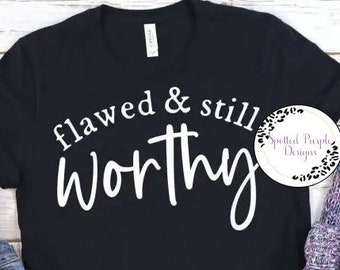 May include: Black t-shirt with white text that reads "flawed & still worthy" with a cross symbol between the words.