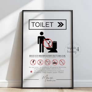 May include: A framed sign with black text and graphics. The sign reads "TOILET" with an arrow, and includes instructions in French and English about disposing of toilet paper only. The sign also features a graphic of a person and a toilet.
