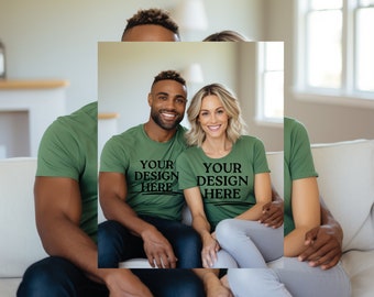 May include: A couple wearing olive green t-shirts with the text "YOUR DESIGN HERE" in black. The man is wearing dark blue jeans, and the woman is wearing gray pants. They are sitting on a white couch. The image includes the text "1 MOCKUP INCLUDED".