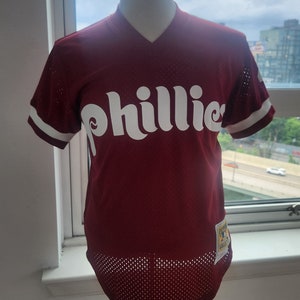 May include: A red mesh baseball jersey with white lettering that says "Phillies".