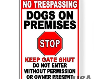 May include: A rectangular red and white sign with black text. The sign reads "NO TRESPASSING DOGS ON PREMISES" with a red "STOP" sign in the center. Additional text includes "KEEP GATE SHUT" and "DO NOT ENTER WITHOUT PERMISSION OR OWNER PRESENT."