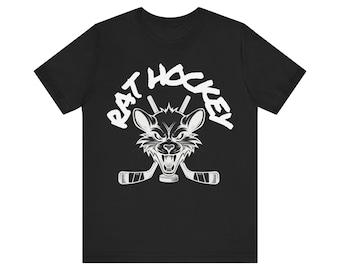 Op de afbeelding: Zwart T-shirt met een witte afbeelding van een boze rat met hockeysticks en de tekst "RAT HOCKEY" erboven. Het ontwerp is gecentreerd op de voorkant van het shirt.