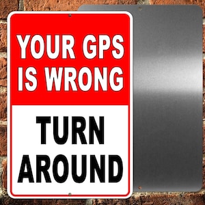 May include: A red and white metal sign with the text "Your GPS is wrong Turn Around". The sign is mounted on a brick wall.