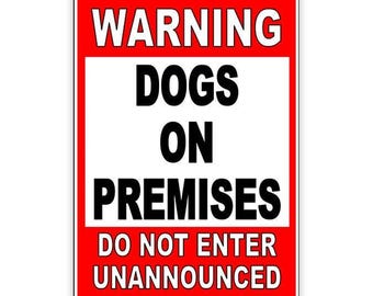 May include: A rectangular red and white sign with black text that reads "WARNING DOGS ON PREMISES DO NOT ENTER UNANNOUNCED". The sign has a white background with a red border.