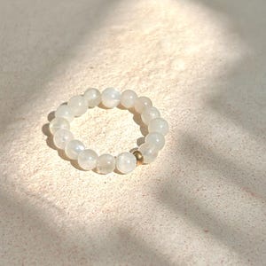 May include: A white moonstone beaded bracelet with a gold accent bead.