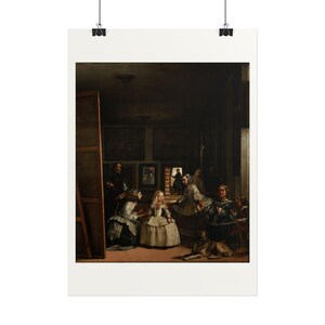 May include: A framed art print of Las Meninas by Diego Velázquez, featuring a central young girl in a white dress surrounded by attendants, a dog, and a painter in a dimly lit room with dark walls and several framed paintings.