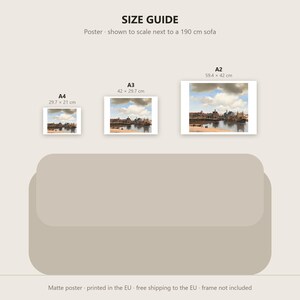 May include: A size guide for a landscape-oriented art print featuring a cityscape painting. The guide displays three rectangular posters in A4, A3, and A2 sizes, positioned above a beige sofa illustration. Text includes SIZE GUIDE.