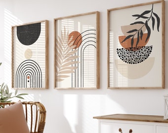 May include: Three framed abstract art prints with geometric shapes and neutral colors hang on a white wall. A wicker chair with a peach-colored pillow and a white blanket sits in front of a window with wooden blinds. A white cabinet with a wooden top and a woven basket complete the scene.
