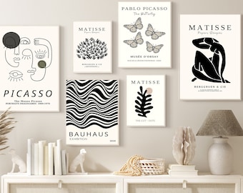 May include: A set of six black and white minimalist art prints featuring abstract designs and text. The prints are framed and hung on a white wall above a white dresser with a wicker basket and a lamp.