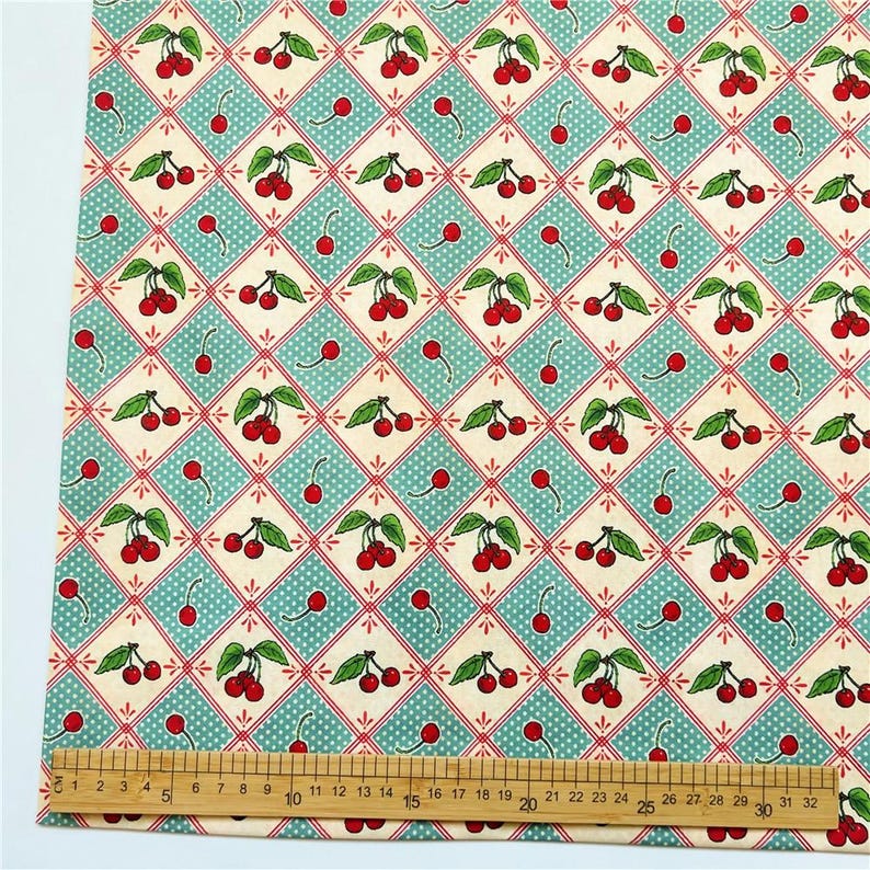 May include: A fabric with a repeating pattern of red cherries with green leaves on a light blue and white checkered background.
