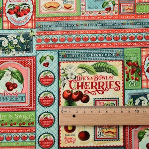 May include: A patterned fabric featuring cherry illustrations, cherry blossoms, and text including "Life's a Bowl of Cherries" and "I Love You Cherry Much," with a wooden ruler measuring 11 cm placed horizontally across the centre of the design.