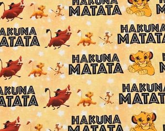May include: A yellow fabric with a repeating pattern of cartoon lions, warthogs, and the phrase "Hakuna Matata".