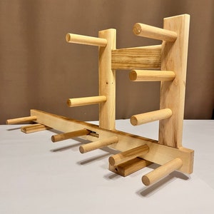 May include: A wooden yarn swift, crafted from light-colored wood. The swift features multiple dowels for holding yarn, arranged in a vertical and horizontal configuration. The design is simple and functional, ideal for yarn organization.