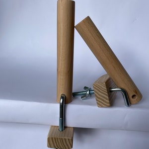 May include: A wooden embroidery hoop stand with two wooden dowels and metal hardware. The stand is designed to hold an embroidery hoop in place while the user works on their project. The wood is a light brown color.