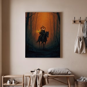 Puede incluir: Una impresión en lienzo con temática de Halloween representa una figura sin cabeza con una cabeza de calabaza montada en un caballo negro a través de un bosque oscuro. La figura sostiene una linterna, y el fondo presenta árboles altos y un brillo naranja.