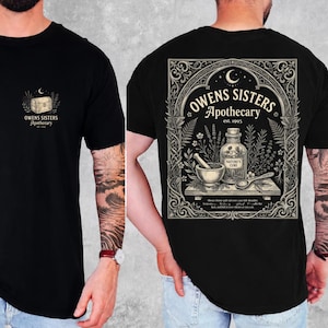 May include: A black t-shirt featuring a small chest graphic of a treasure chest and the text "Owens Sisters Apothecary est. 1995". The back displays a large, ornate rectangular design with a mortar, pestle, and bottle labelled "Nature's Cure".