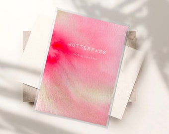 May include: A rectangular Mutterpass cover featuring a soft pink and white watercolor wash design. The text MUTTERPASS and -VOR & ZUNAME- are printed in white on the front. The cover is encased in a clear protective sleeve.