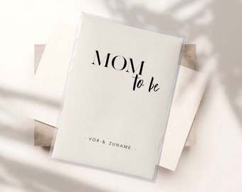 May include: A rectangular white card enclosed in a clear plastic sleeve. The card features the black printed text MOM to be in a combination of serif and script fonts, with the text - VOR- & ZUNAME - printed in a simple sans-serif font below.