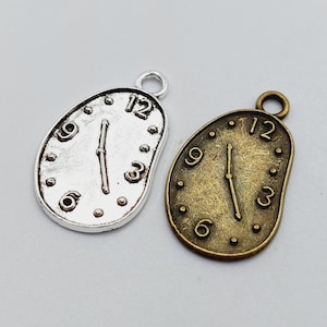 Peut inclure: Deux breloques en forme de montre à fusion, l'une en argent et l'autre en bronze, avec un cadran d'horloge en chiffres romains.