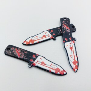 May include: Three black plastic knives with red blood splatter designs.