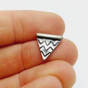 May include: Silver triangle pendant with a chevron pattern.